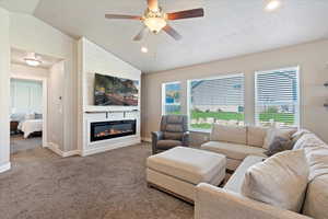 Carpeted living room featuring vaulted ceiling, a textured ceiling, and baseboards