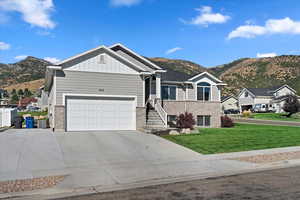 View of front of house featuring brick siding, an attached garage, a mountain view, board and batten siding, and a front yard