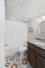 Bathroom featuring toilet, vanity, and a textured ceiling