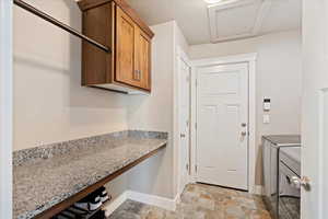 Washroom featuring cabinet space, washing machine and dryer, baseboards, and stone finish flooring