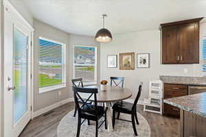 Dining space featuring a textured ceiling, wood finished floors, visible vents, and baseboards