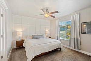 Carpeted bedroom with a ceiling fan and baseboards