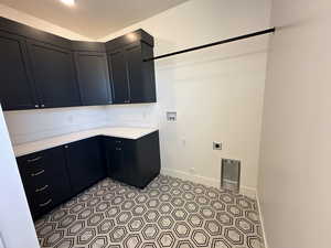 Clothes washing area featuring light tile patterned floors, washer hookup, baseboards, cabinet space, and electric dryer hookup