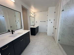 Bathroom featuring a stall shower, baseboards, a sink, marble finish floor, and two vanities