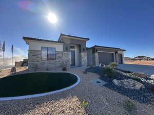 Prairie-style home featuring a garage, stone siding, concrete driveway, and stucco siding