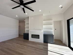 Unfurnished living room featuring built in shelves, a fireplace, visible vents, and dark wood finished floors