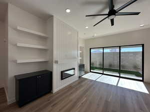 Unfurnished living room with built in shelves, a fireplace, wood finished floors, and baseboards