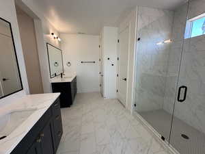 Full bathroom featuring marble finish floor, a sink, a marble finish shower, and baseboards