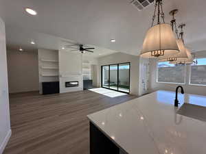 Kitchen with visible vents, open floor plan, dark wood-style flooring, decorative light fixtures, and light stone countertops