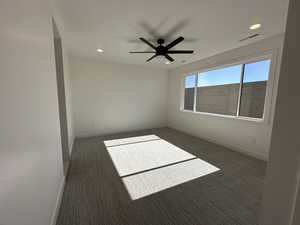 Spare room featuring recessed lighting, dark carpet, visible vents, and baseboards