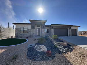 Prairie-style house with a garage, stone siding, concrete driveway, and stucco siding