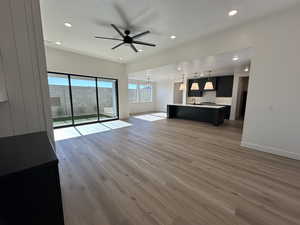 Unfurnished living room with ceiling fan with notable chandelier, recessed lighting, baseboards, and wood finished floors