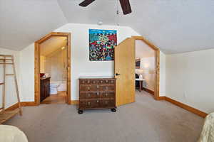 Additional living space with light carpet, vaulted ceiling, and a textured ceiling