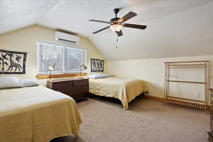 Carpeted bedroom with lofted ceiling, a wall mounted AC, ceiling fan, a textured ceiling, and baseboards