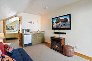 Living area featuring a toaster, baseboards, light colored carpet, vaulted ceiling, and a textured ceiling