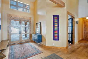 Foyer entrance featuring light wood-style floors, french doors, and a towering ceiling