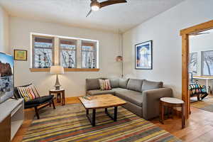 Living area with ceiling fan, a textured ceiling, and wood finished floors