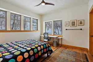 Bedroom featuring a textured ceiling, wood finished floors, a ceiling fan, and baseboards