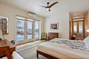 Bedroom featuring access to exterior, french doors, light wood-style floors, a mountain view, and a wall mounted AC