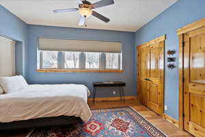 Bedroom featuring baseboards, ceiling fan, a textured ceiling, and light wood finished floors