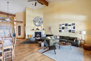 Living room with light wood-type flooring, a fireplace, high vaulted ceiling, and beam ceiling