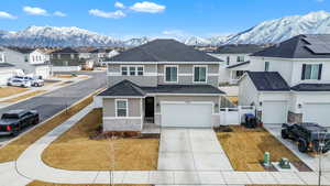 View of front facade with a shingled roof, concrete driveway, stone siding, a residential view, and a mountain view