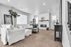 Living area with a healthy amount of sunlight, a fireplace, light wood-style flooring, and a textured ceiling