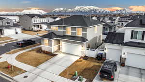 View of front of home with driveway, stone siding, a residential view, fence, and a mountain view