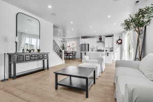 Living area featuring light wood-style flooring, stairs, a chandelier, and recessed lighting