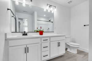 Bathroom featuring wood finished floors, walk in shower, a sink, and visible vents