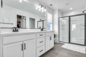 Bathroom featuring a stall shower, a walk in closet, visible vents, and wood finished floors