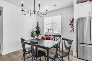 Dining space with a chandelier, baseboards, visible vents, and light wood finished floors