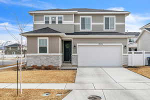 View of front of property with stone siding, fence, driveway, and stucco siding