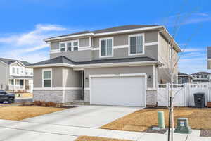 Prairie-style house with stone siding, an attached garage, concrete driveway, and stucco siding