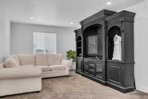 Living area featuring a textured ceiling, carpet, baseboards, and recessed lighting