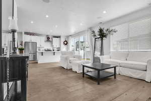 Living room with light wood-type flooring, visible vents, a textured ceiling, and recessed lighting