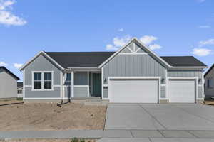 View of front of property with board and batten siding, an attached garage, concrete driveway, and roof with shingles
