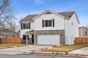 View of front of house featuring a garage, concrete driveway, brick siding, and fence