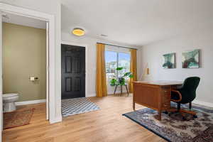 Office space with light wood finished floors, visible vents, and baseboards