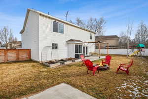 Rear view of house featuring an outdoor fire pit, a fenced backyard, a yard, a patio area, and a playground