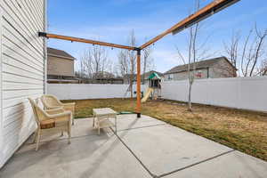 View of patio with a playground and a fenced backyard