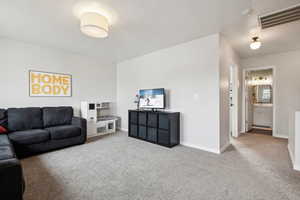 Carpeted living area with visible vents and baseboards