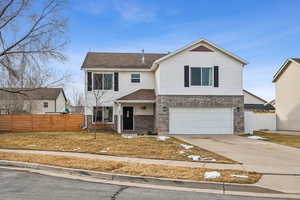 Traditional-style home featuring driveway, brick siding, and fence