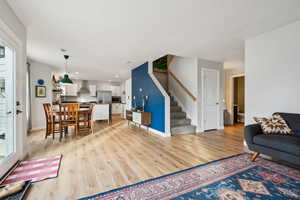 Living room with stairs, light wood-type flooring, and baseboards