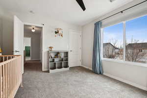 Carpeted bedroom with ceiling fan and baseboards