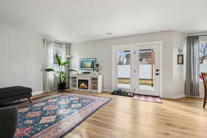 Interior space featuring light wood finished floors, a warm lit fireplace, visible vents, and baseboards