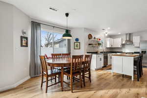 Dining area with light wood finished floors, baseboards, visible vents, and recessed lighting