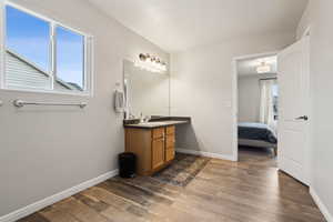 Ensuite bathroom featuring plenty of natural light, baseboards, wood finished floors, and vanity