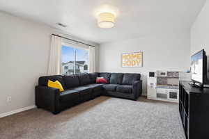 Carpeted living area featuring baseboards and visible vents