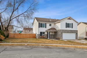 View of front of property with a garage, brick siding, fence, driveway, and a front yard